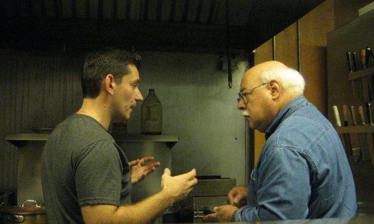 Chef Daniel Aguera and Chris Fennimore talk about cooking in front of a restaurant grill